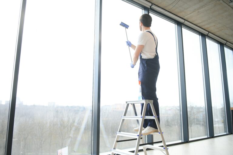 An employee of a professional cleaning service washes the glass of the windows of the building. Showcase cleaning for shops and businesses.